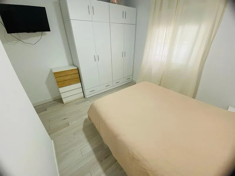 Dormitorio principal con cama, armario blanco y cómoda de madera