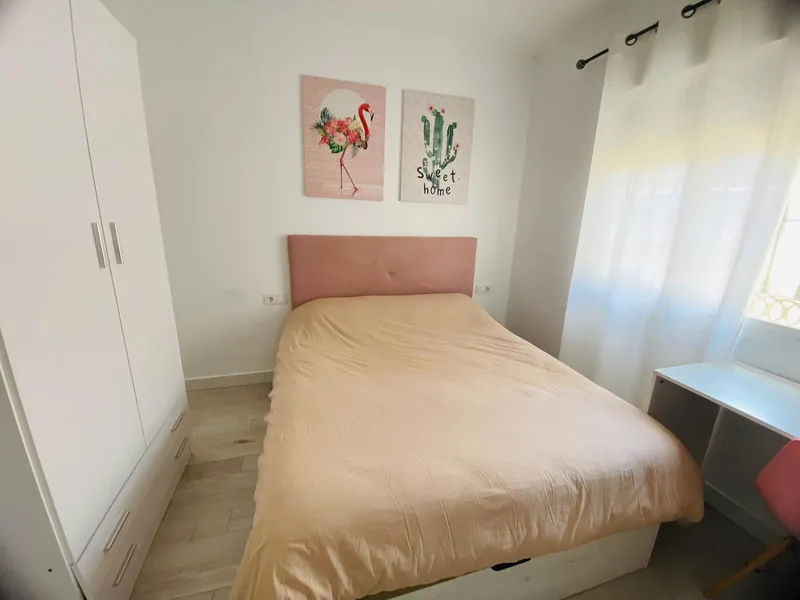 Dormitorio con cama, armario blanco y escritorio junto a la ventana