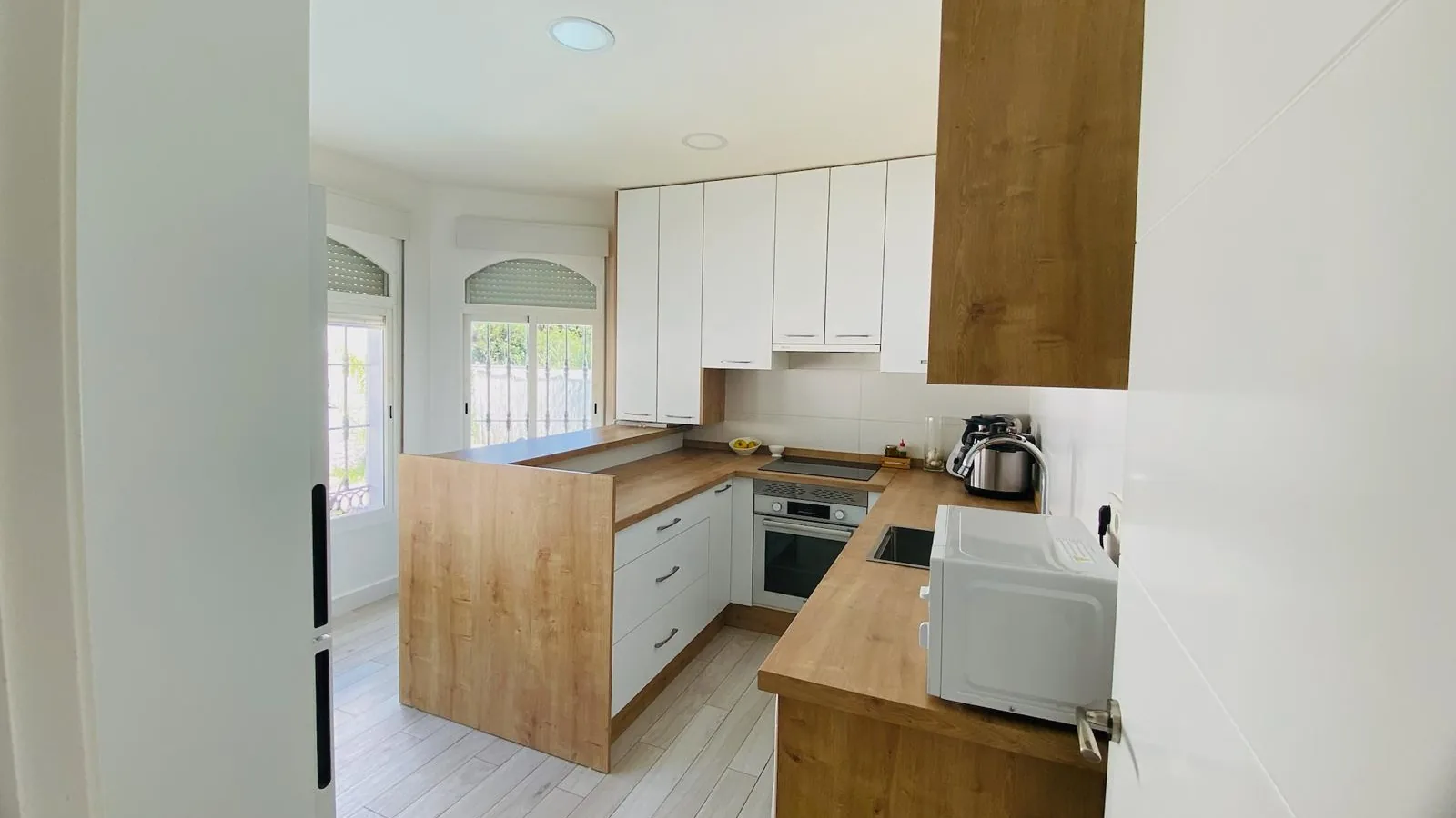 Acceso a la cocina blanca con encimeras de madera