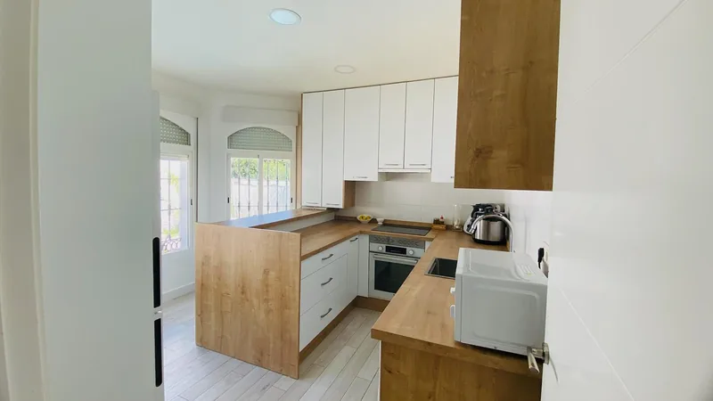 Acceso a la cocina blanca con encimeras de madera