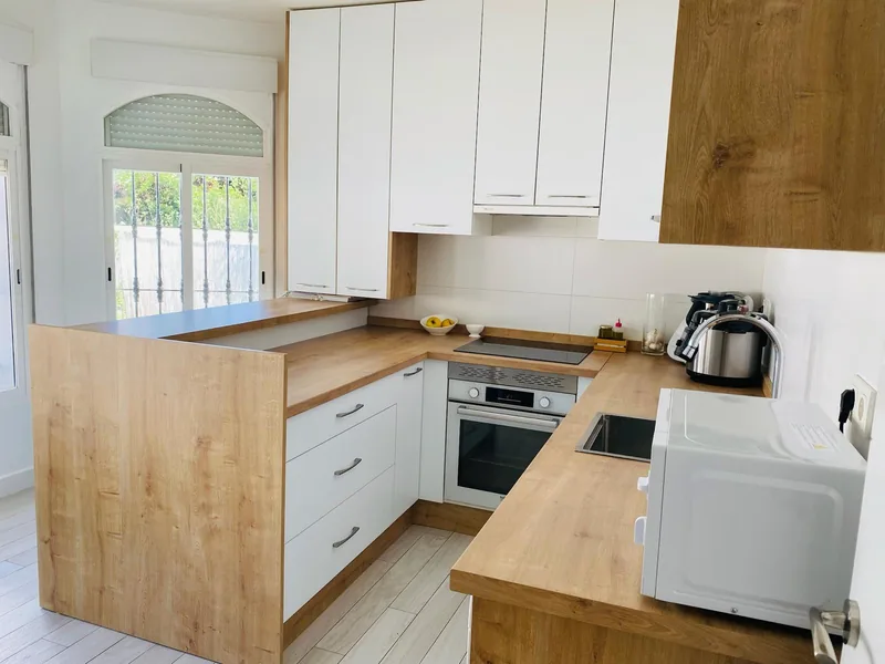Cocina en U con península de madera y armarios blancos
